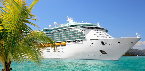 A large cruise ship docked in tropical waters near a sandy beach